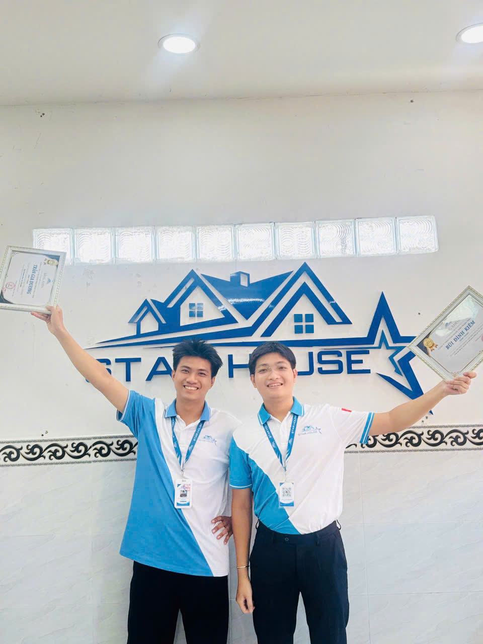 Hai nhân viên Star House khoe giấy khen trước logo công ty